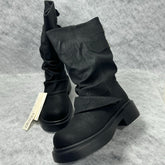Stacked boots in a creased heap